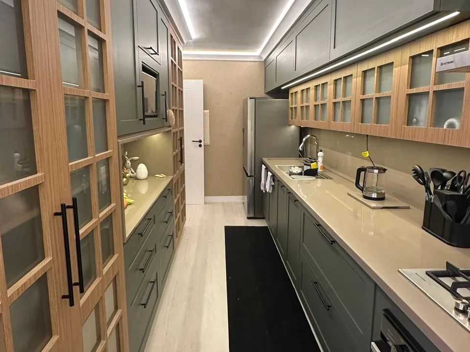 Cozinha linear com marcenaria e perfis de luz no teto